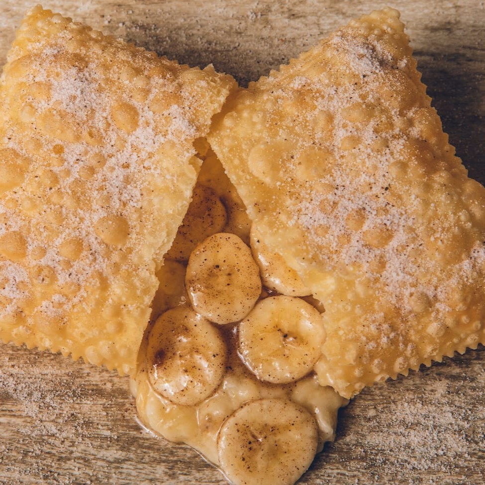Deliciosa massa crocante polvilhada com açúcar e canela recheado de banana e canela. Sugestão: Nosso pastel de banana combina perfeitamente com a borda de chocolate, experimente essa combinação e nos conte o que achou! (Tamanho 10 x 7 Cm)