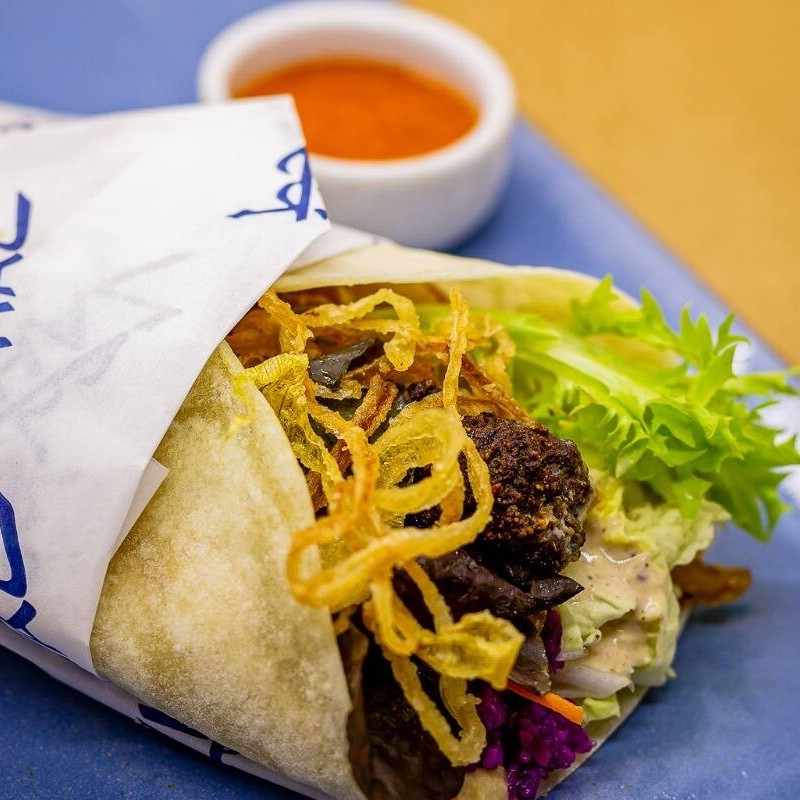 Pão folha, kafta, homus, acelga, cenoura, picles de repolho roxo, cebola frita e tahine