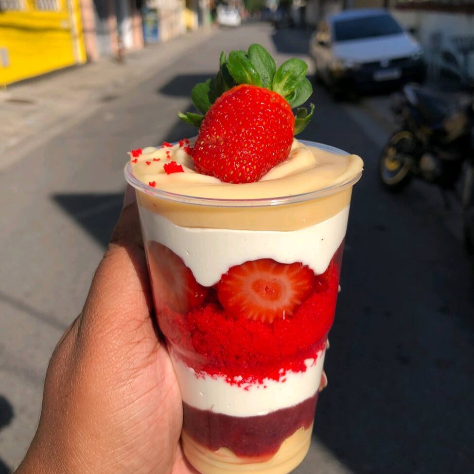 Um delicioso copo da felicidade red velvet com nosso famoso brigadeiro de Ninho e nossa geleia de morango caseira e morangos picados.