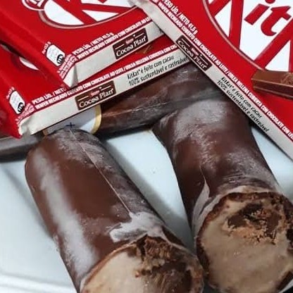 O sacolé de Kit Kat é uma verdadeira explosão de sabor e textura! Ele começa com um cremoso sorvete de chocolate, que envolve um recheio ainda mais intenso do mesmo sabor, misturado com pedaços crocantes de Kit Kat. No centro, como uma deliciosa surpresa, há uma barrinha inteira de Kit Kat, trazendo aquele toque extra de crocância e sabor inconfundível do chocolate ao leite com wafer. Cada mordida combina a cremosidade do sorvete com o crocante irresistível do Kit Kat, tornando essa sobremesa uma experiência única e irresistível!