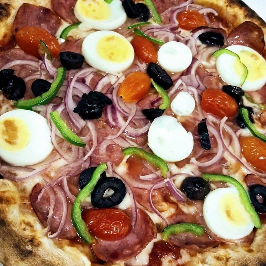 Pizza irresistível com molho pelati, muçarela de búfala cremosa, cebola, pimentões frescos, tomate suculento, ovo cozido perfeito, calabresa, azeitonas pretas e um toque de orégano.