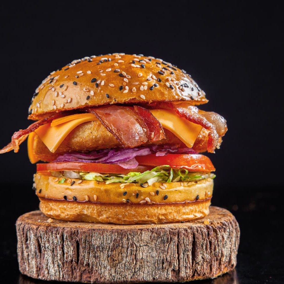 Pão brioche Gergelim, hamburguer de frango chicken supreme Seara, fatia de queijo cheddar , fatias de bacon crocante , salada e maionese surreal