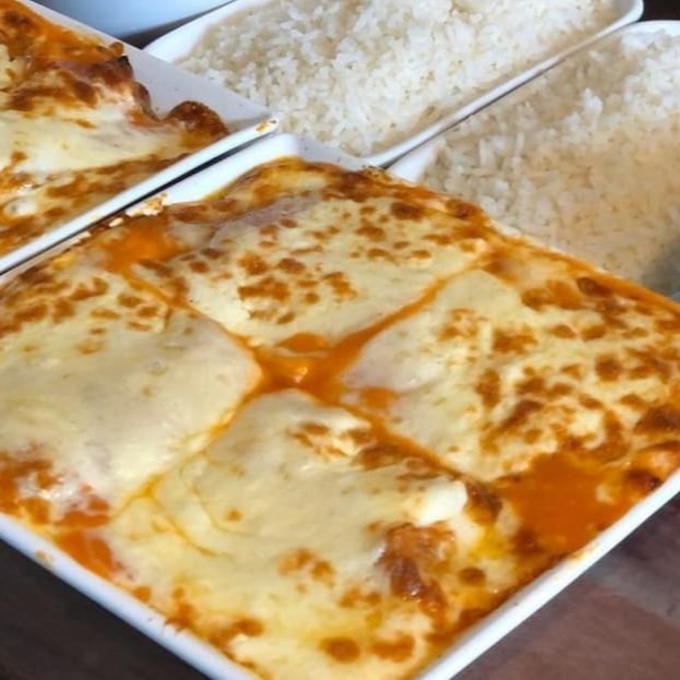 File de frango empanado e frito , gratinado com queijo mussarela e molho de tomate acompanhado de arroz e uma guarnição a escolha