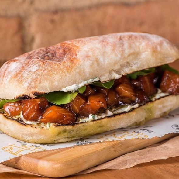 Pão ciabatta, salmão marinado em cubos, cream cheese, rúcula, pesto, coentro e teriaky.