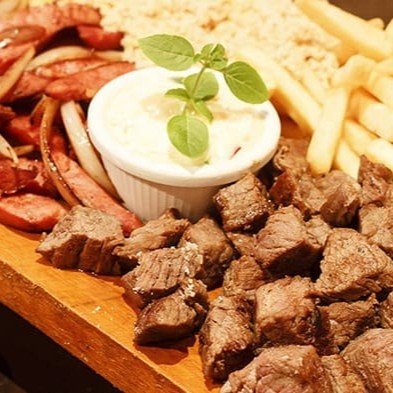 Este prato inclui 600g de linguiça toscana suculenta, tiras de frango grelhadas e alcatra macia, oferecendo uma mistura perfeita de sabores e texturas. Tudo é servido com uma deliciosa farofa do Chef, que adiciona um toque crocante e saboroso ao conjunto.