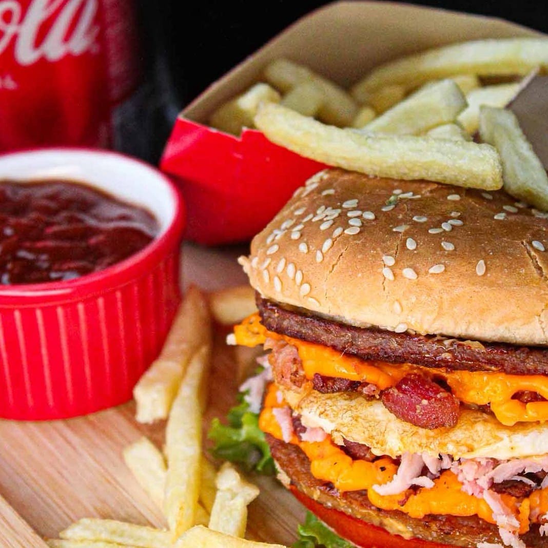 Pão com gergelim, 2 carnes,  cheddar, presunto, ovo, bacon, alface, tomate e molho especial. + coca lata e batata frita