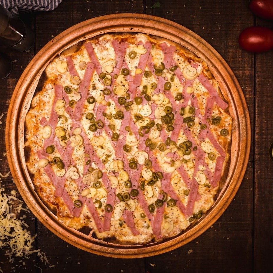Pizza com tiras de presunto, azeitonas verdes fatiadas e aquele delicioso champignon fatiado