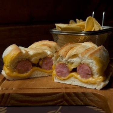 Pão Artesanal com linguiça de pernil recheada com provolone e maionese de chimichurri e batata chips. O Sanduiche especial da casa ainda conta com o pão artesanal italiano e queijo prato.