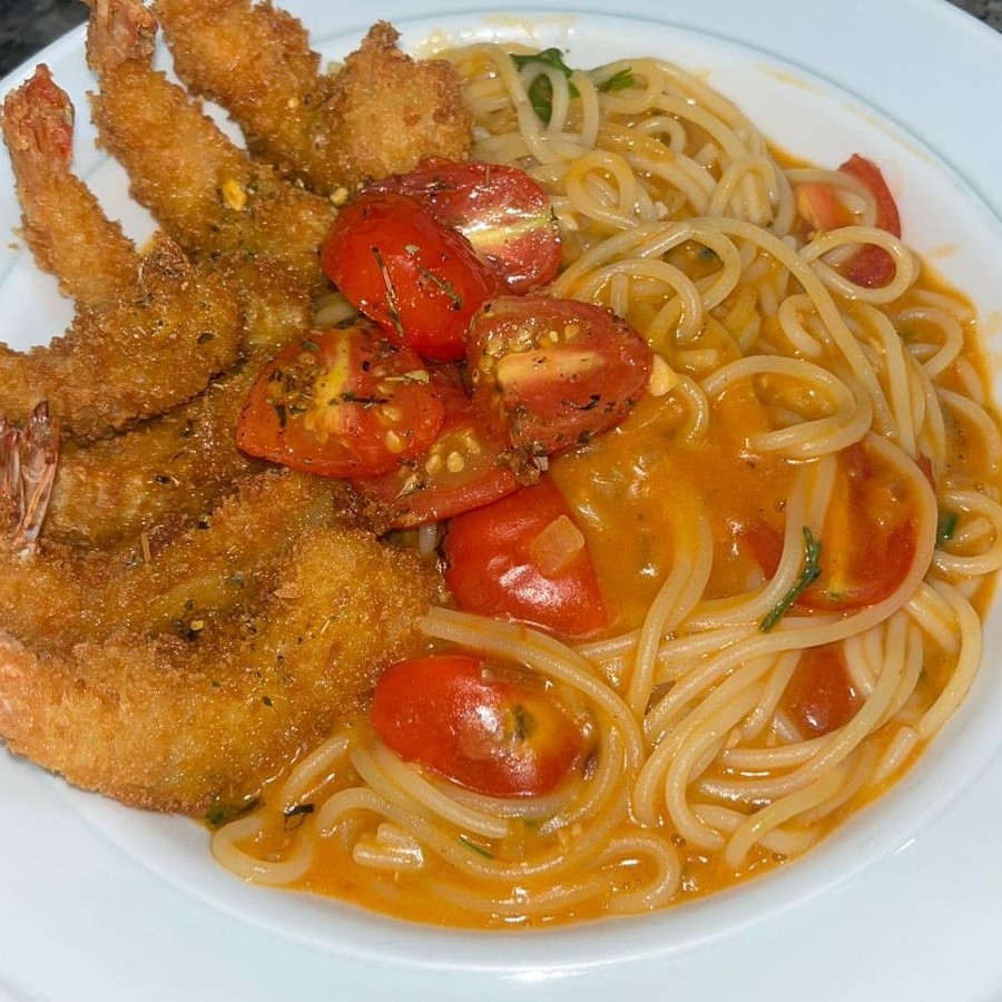Porção de camarão empanado acompanhado de espaguete com molho de camarão e tomates