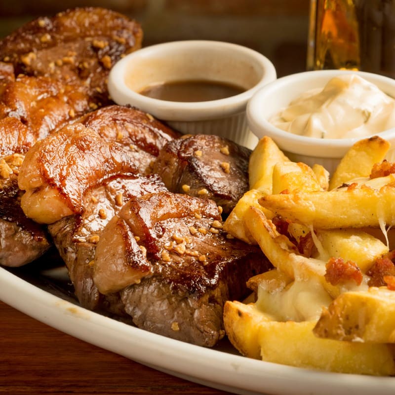 Suculenta picanha fatiada, acompanhada por batata frita 14mm coberta com mix de queijos e bacon, acompanha separadamente molho ranch e molho Cabernet.