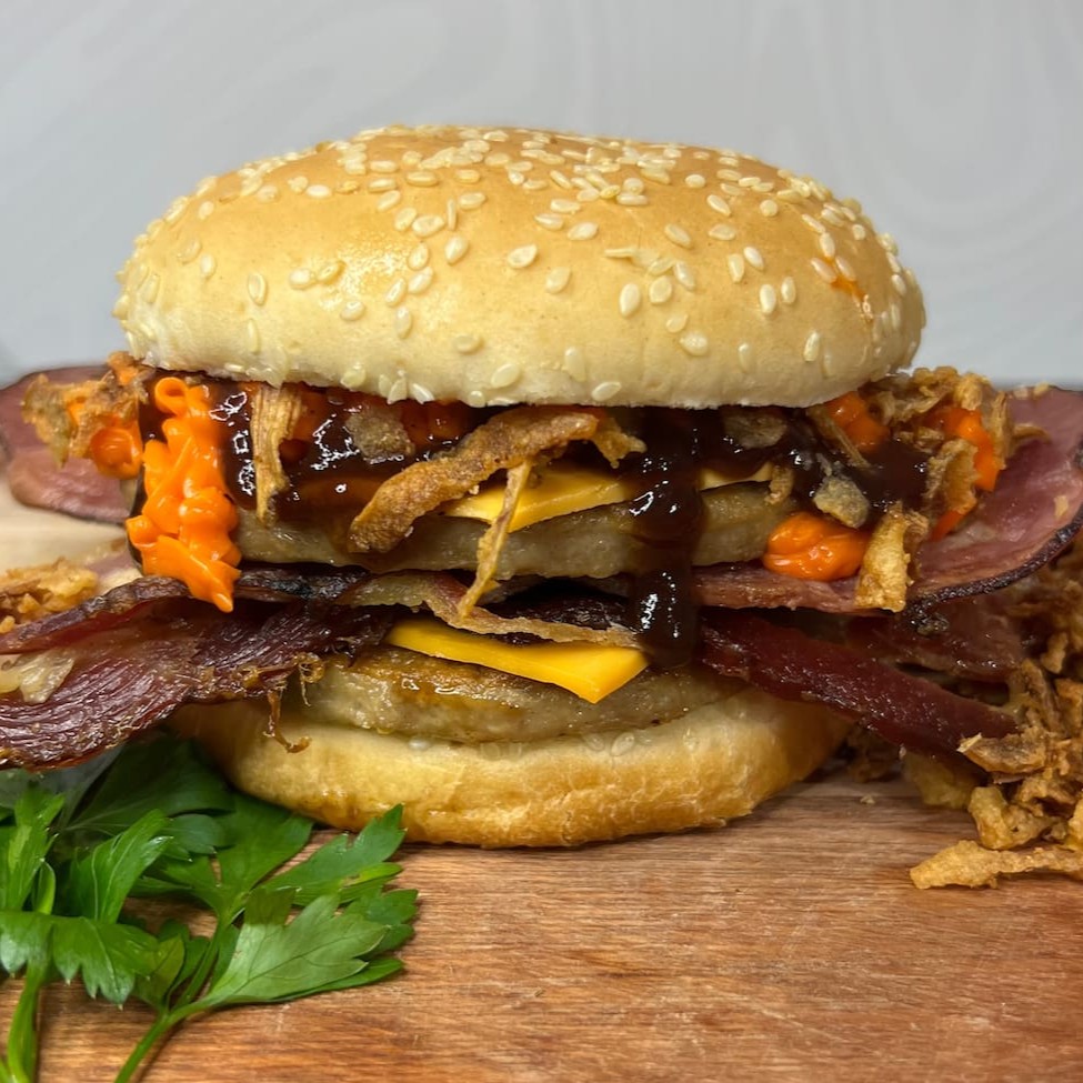 Pão, 2 carnes, 2 fatias de queijo mussarela, 3 fatias de bacon, cebola crispy, cheddar cremoso em dobro e barbecue.