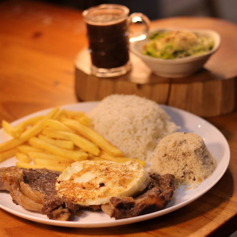 Marmita executiva acompanha: arroz branco, feijão preto, farofa, batata frita e salada de alface com tomate e cebola.
