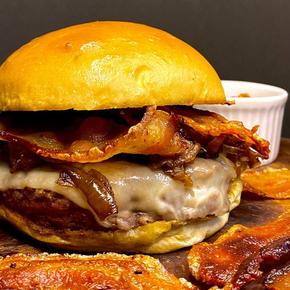 180g do Nosso Blend Bovino, Bastante Queijo, Bacon Crocante, Cebola Caramelizada e Maionese da Casa no Pão Artesanal.