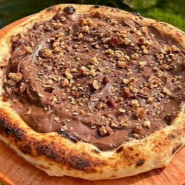 Pizza artesanal, fermentada por 100 horas, com molho feito 100% com carinho e ingredientes naturais, livre de industrializados e aditivos. Leva Nutella e Avelãs crocantes.