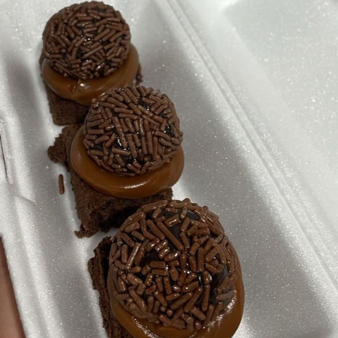 Pedaço de bolo de chocolate com cobertura de doce de leite e docinho de brigadeiro em cima