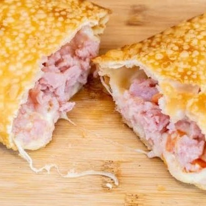 Pastel Presunto Supremo  Simples, mas com sabor surpreendente! Recheado com presunto fatiado de primeira, mussarela derretida, Catupiry cremoso e cebola crocante para dar aquele toque especial. Um pastel equilibrado, macio por dentro e crocante por fora — perfeito para quem ama uma combinação clássica com um toque de sofisticação!    Imagem ilustrativa.