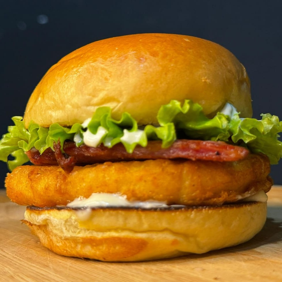 Pão de brioche, frango empanado, queijo cheddar, bacon, alface e maionese da casa