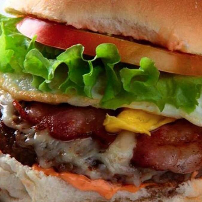 Apresentamos o nosso 'X Yakuza', uma estrela da categoria 'Yakuza Burguers'. Este hambúrguer é uma combinação sublime de suculenta carne bovina com um ovo perfeitamente cozido, envolto em fatias de bacon crocante. O toque final fica por conta de uma generosa camada de queijo cheddar derretido, complementado por uma cama fresca de alface, fatias de tomate vibrante e cebola crocante. Cada mordida é uma experiência culinária memorável, repleta de sabor e texturas contrastantes. Uma verdadeira delícia que aguça os sentidos e deixa um desejo persistente por mais.