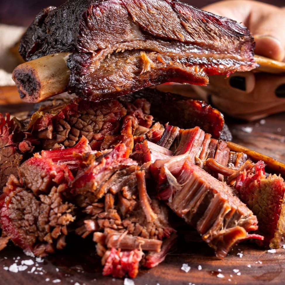 Rainha da Casa. Costela bovina maturada cuidadosamente assada na lenha frutífera de macieira por 12 horas, resultando suculência e sabor defumado inigualável. Sem osso e sem excesso de gordura.