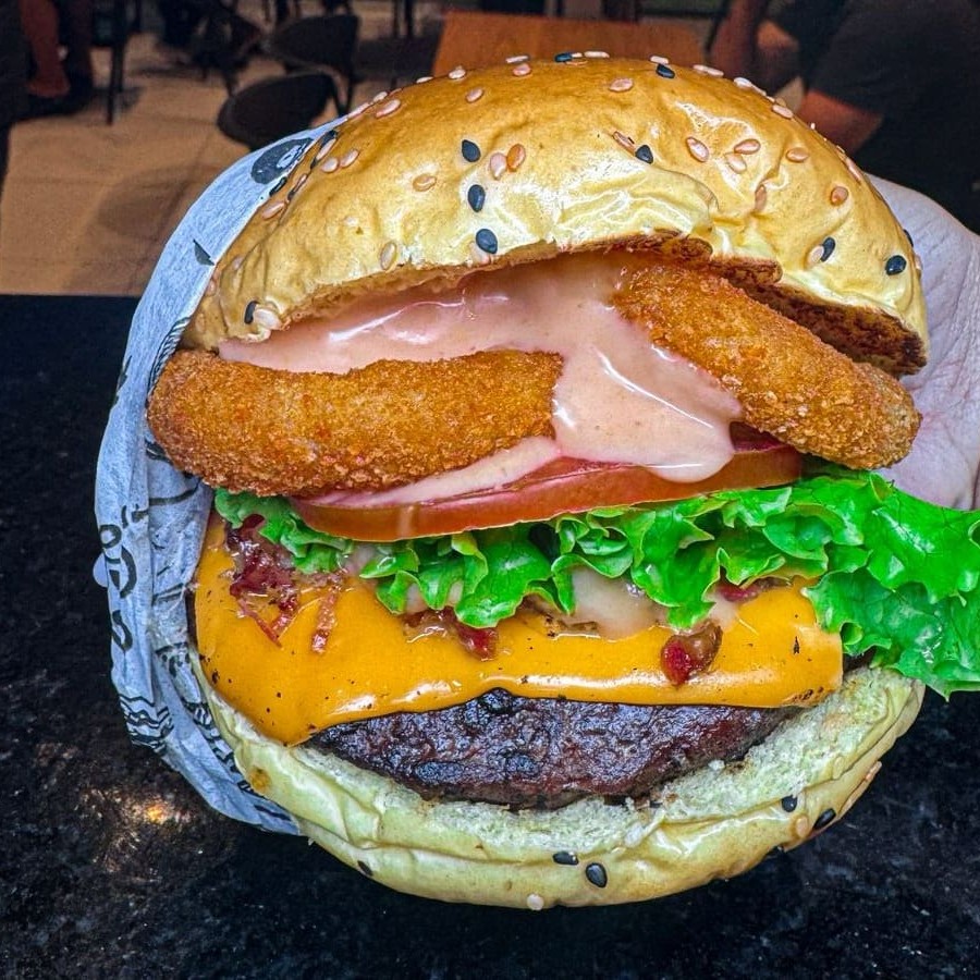 O Matador De Larica! Pão vermelho de pimenta biquinho(não arde), blend 160g com queijo cheddar derretido no vapor, bacon triturado, onion (anel de cebola), alface, tomate e molho mac