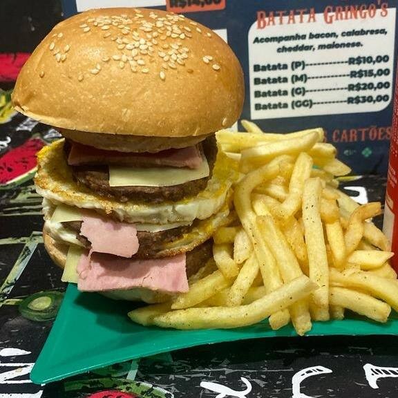 O 'Triplo Cheddar', da categoria Lanches, é uma opulenta experiência gastronômica. Este lanche é generosamente empilhado com três suculentas carnes, todas realçadas com um rico e cremoso cheddar. O sabor defumado do bacon agrega uma nota de sabor inesperada, enquanto o ovo adiciona uma textura suave e satisfatória. A maionese temperada e o ketchup trazem o equilíbrio perfeito de temperos, criando uma combinação de sabores inesquecível. É um prato indulgente e definitivamente não para os fracos de coração!