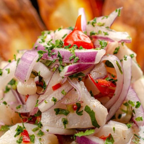 """Ceviche fresco e vibrante, preparado com pedaços suculentos de peixe marinados em suco de limão, realçados por temperos especiais que trazem um equilíbrio perfeito entre acidez e sabor. Com toques de cebola roxa, coentro fresco e pimenta suave, essa iguaria típica oferece uma explosão de frescor e leveza em cada garfada, ideal para quem busca uma experiência gastronômica leve e saborosa."""