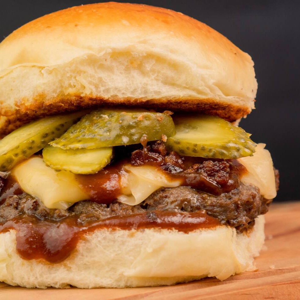 "• No pão brioche, 1 blend de 180g vem acompanhado de molho barbecue, uma deliciosa farofa de bacon com bastante mussarela e fatias de picles.   ponto da casa:""ao ponto p/mal"". Caso desejar sua carne em outro ponto, por favor especificar na observação.  Foto ilustrativa."