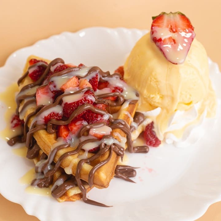 Waffle, Nutella (aí já apelamos, né?), leite condensado, sorvete de creme, morango e chantilly. Imagem meramente ilustrativa.