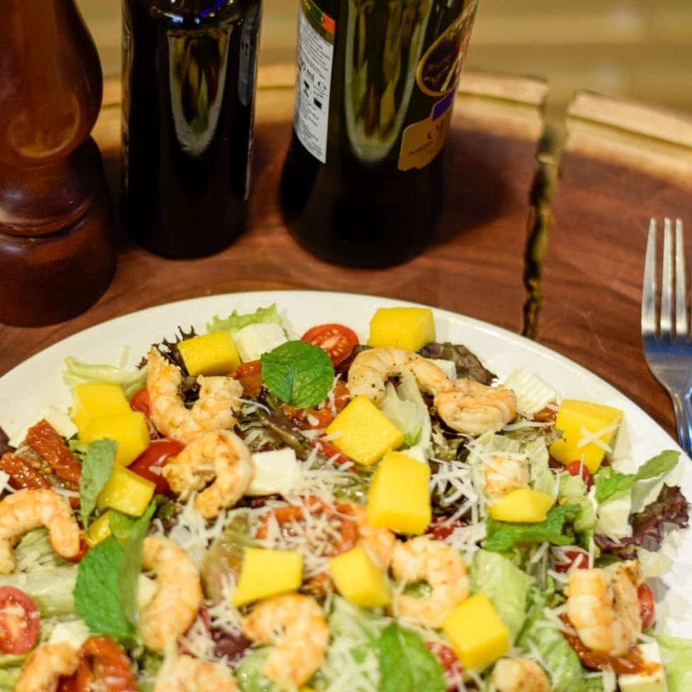 405 - Salada Tropical. Uma explosão de sabores exóticos e refrescantes! Camarões ou salmão flambados, proporcionando um toque sofisticado. Dois tipos de alface crocantes, combinados com tomates grape frescos e tomates secos suculentos. A manga acrescenta notas doces e tropicais à mistura. Acompanha um duplo deleite de queijos: o suave Minas e o robusto Parmesão. Para finalizar, hortelã fresca, trazendo um aroma inconfundível. Personalize com até dois dos nossos molhos especiais: Caesar, Caseiro, Vinagrete, Mostarda e Mel, Rosé ou Italiano. Uma salada perfeita para quem busca uma refeição leve e cheia de personalidade.  Atenção: Escrever Na Observação Com Salmão Ou Camarão Sem Observação Será Feito Com Camarão Obrigado!