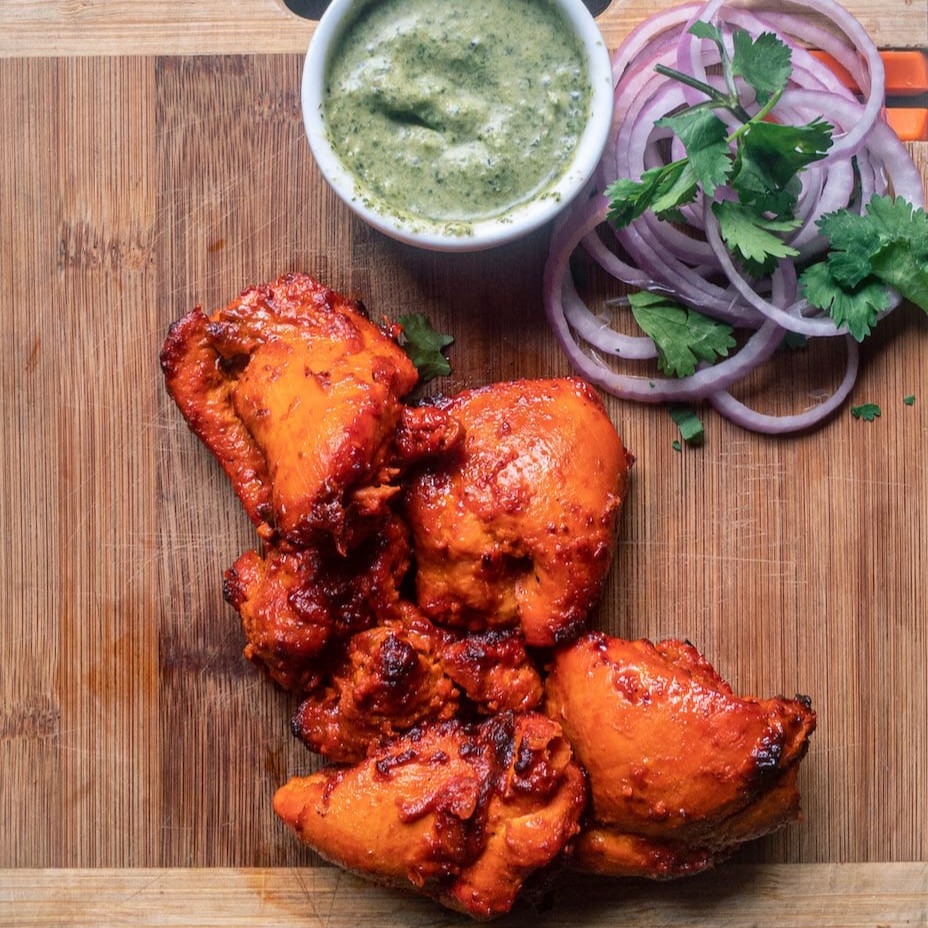 Deliciosos pedaços de sobrecoxa de frango marinados na pasta especial de coalhada e especiarias selecionadas. assado no forno tandoor. acompanha chutney de hortelã. - 8 unidades