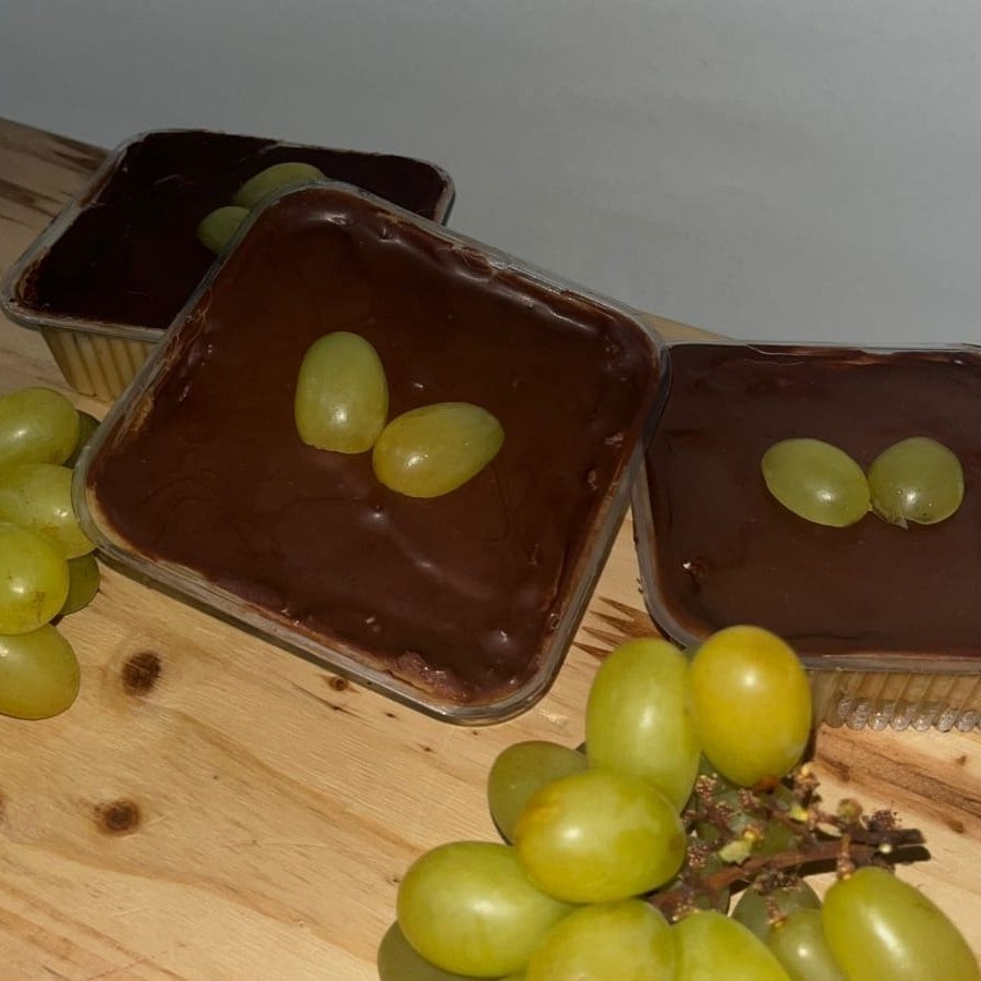 Pote com camadas de brigadeiro de Ninho com pedaços de uva e uma camada crocante de chocolate ao leite por cima.