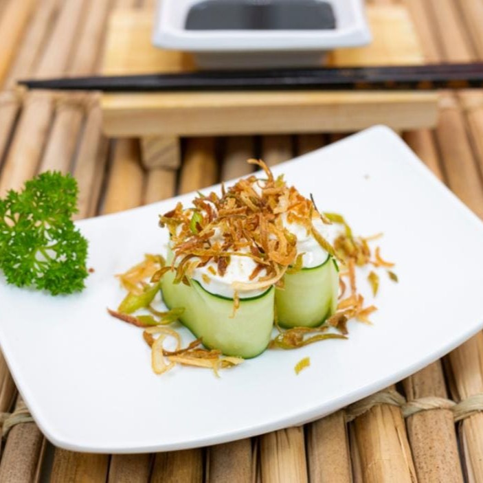 Base de arroz, envolto por lâmina de pepino com cream cheese ou cajupiry (vegano) e palha de alho poró.