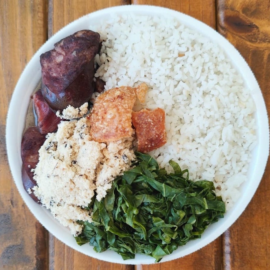 Deliciosa quentinha de Feijoada completa com couve manteiga refogada, farofa da casa, arroz branco e torresmo crocante. Marmita na porção mini indicada para 01 pessoa com 1kg. Comida quentinha, feita na hora do seu pedido!