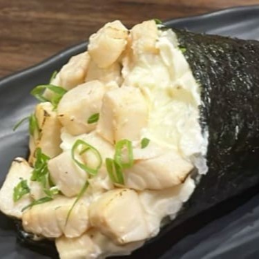 """Haru Temaki Philadelphia elaborado com alga crocante e arroz temperado na medida certa, recheado com o clássico salmão fresco e cream cheese cremoso, combinado com uma delicada pasta de peixe branco que traz suavidade e um sabor único ao conjunto. Enrolado na hora para garantir frescor, textura e uma experiência gastronômica surpreendente a cada mordida."""