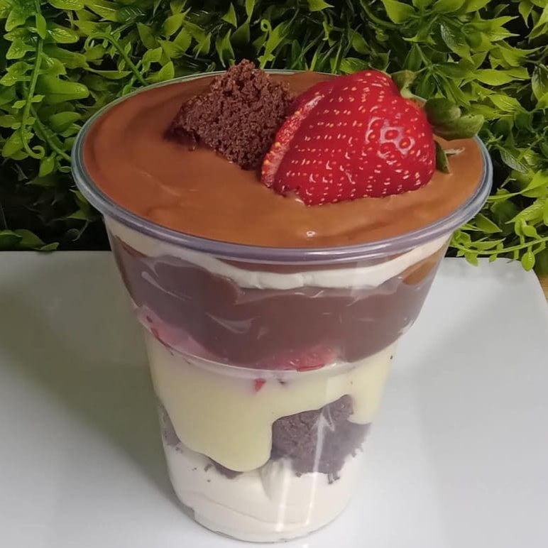 Mousse de leite Ninho, pedaços de brownie, recheio de chocolate branco, morangos em pedaços, recheio de chocolate e finalizado com brownie e morango.