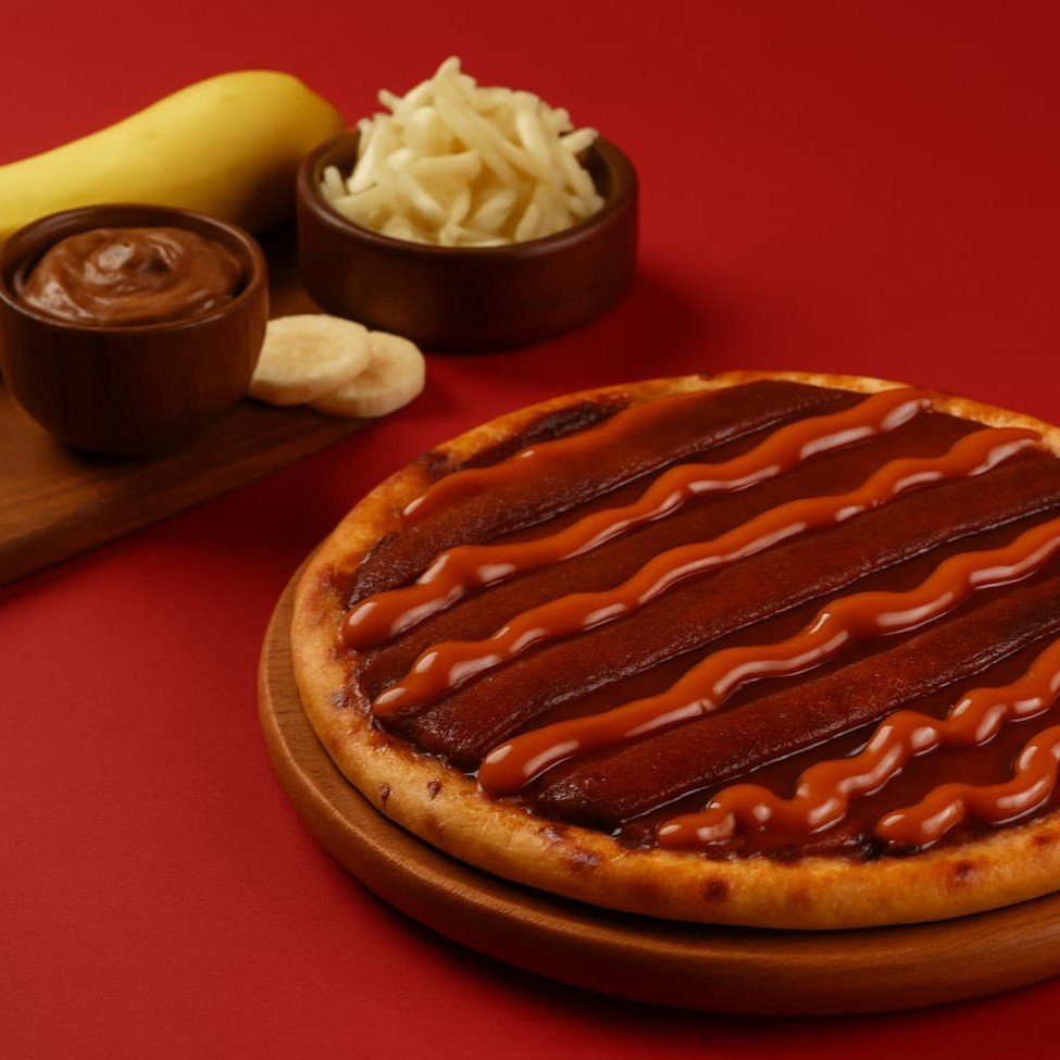 A nossa 'Pizza Broto Banana Especial Nevada' é a opção doce mais adorada pelos nossos clientes. Ela combina de maneira perfeita e harmoniosa a doçura das bananas frescas, cuidadosamente selecionadas, com a doçura aconchegante do açúcar e o toque aromático da canela. O chocolate branco crocante adiciona uma textura surpreendente e irresistível, enquanto o doce de leite casado com todos esses ingredientes, traz uma cremosidade única e inigualável. Ideal para finalizar um jantar bom e barato com um sabor marcante e delicioso.