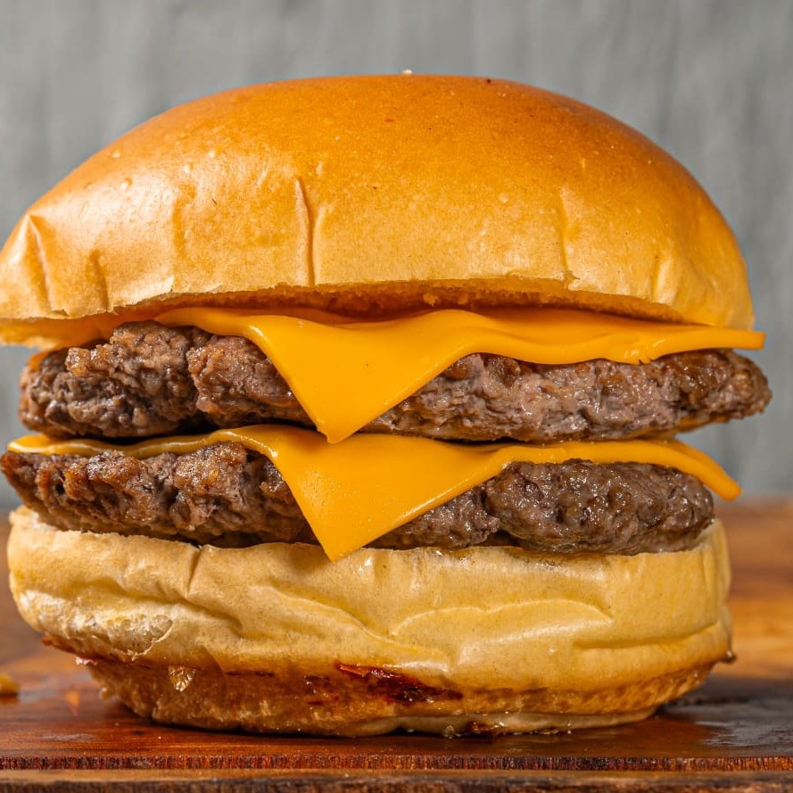 Pão brioche selado, 2 carnes smash 90g, 2 queijos. Adicione os seus complementos.