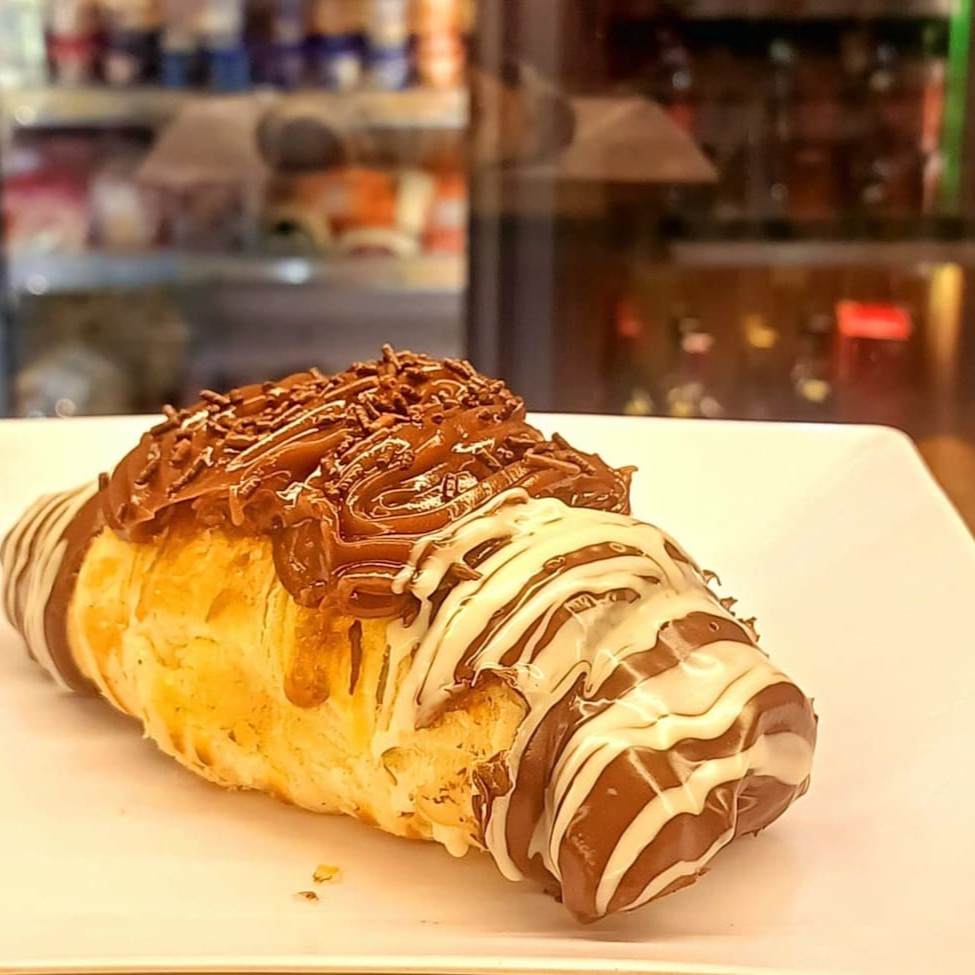 Desfrute de nosso delicioso 'Croissant Folheado de Chocolate'. Um primor da confeitaria, este deleite é meticulosamente preparado com camadas finas e crocantes de massa folhada, envolvendo um recheio luxuoso de chocolate. O sabor rico do chocolate harmoniza perfeitamente com a textura leve e estaladiça do croissant, criando uma experiência culinária doce e satisfatória. Este é, sem dúvida, um prato irresistível para os amantes de doces e uma especialidade imperdível de nossa categoria de 'Confeitaria Doces'.