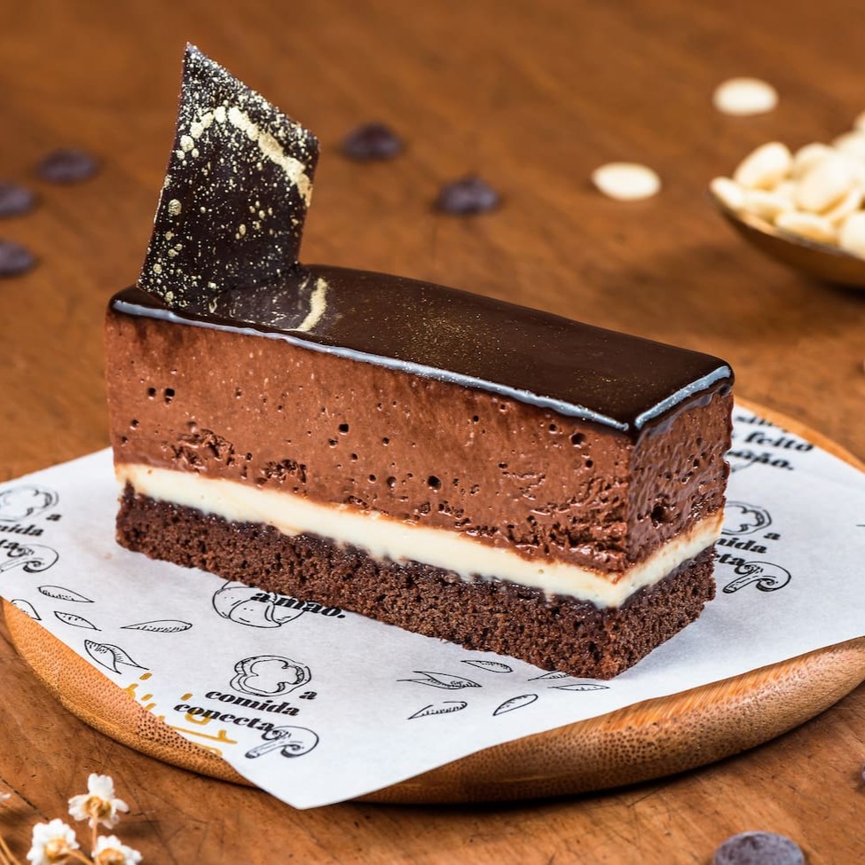 Biscuit Genoise, mousse de chocolate meio amargo belga com ganache de chocolate branco belga.  Finalizado com glaçagem de cacau.