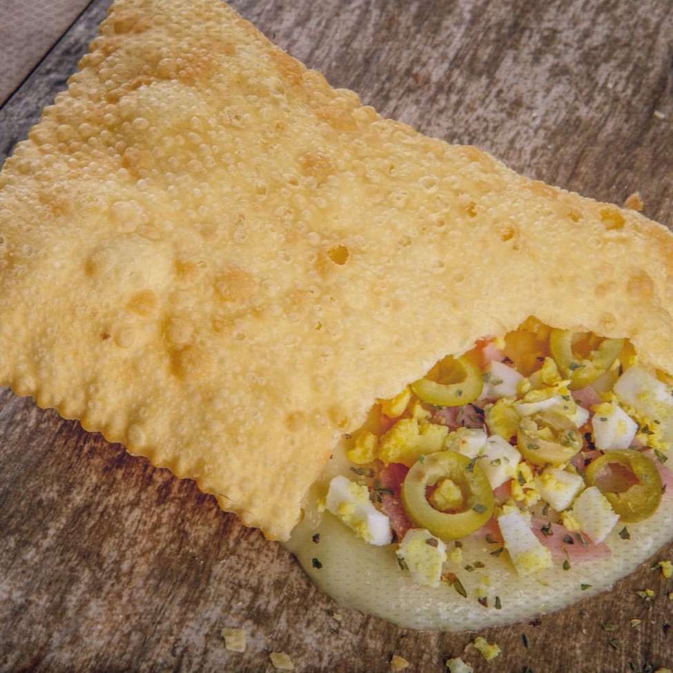 Delicioso pastel de massa crocante recheado com muçarela, presunto, ovo, azeitona e orégano