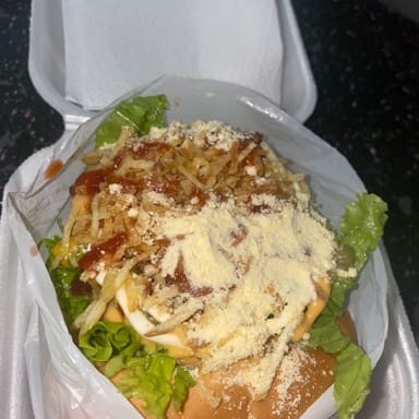 Pão, Carne, ovo, caprichado no bacon, queijo, presunto, alface, ketchup, maionese, mostarda, molho Billy Jack, cheddar, milho, ervilha, queijo ralado, batata palha, e molho verde