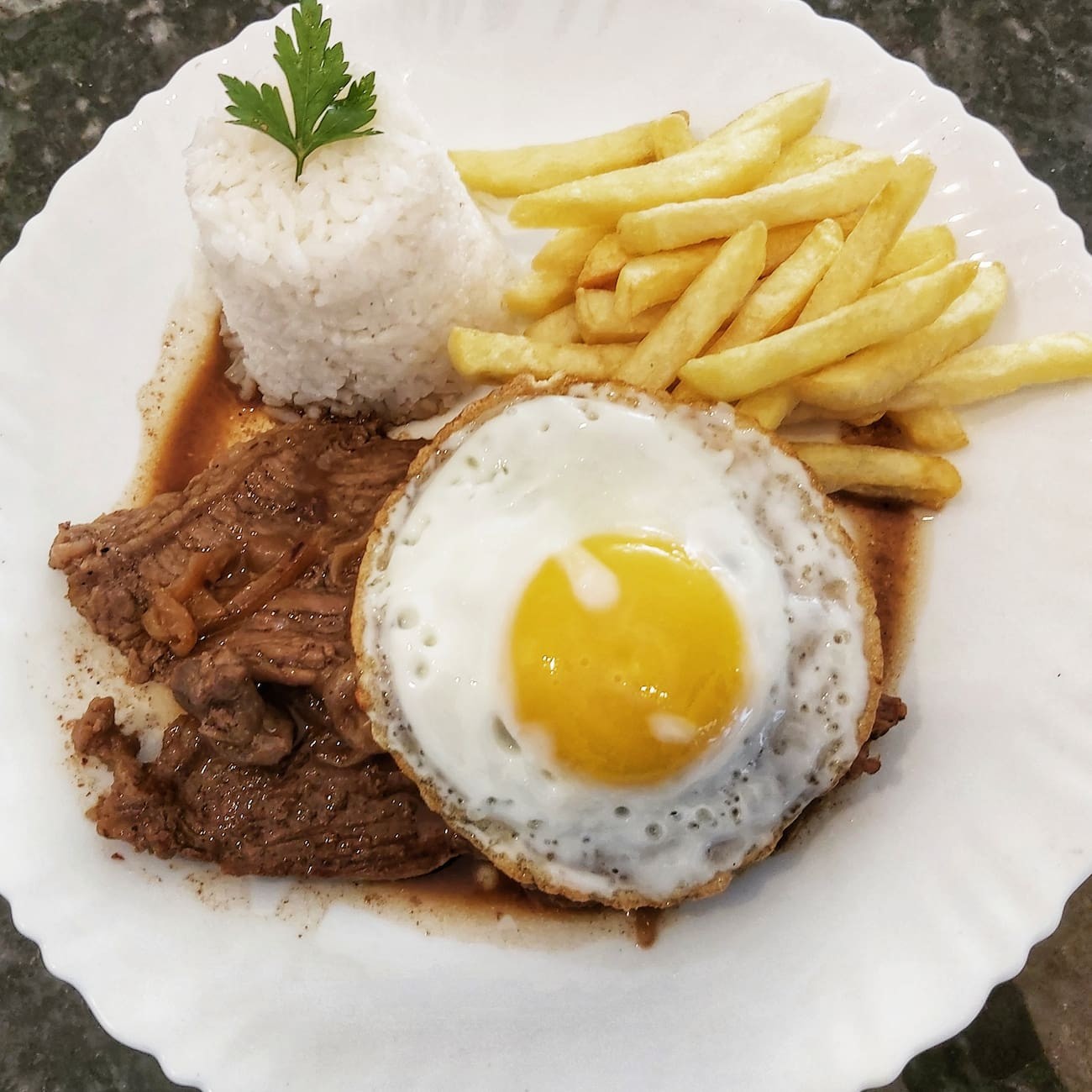O Bife à Cavalo do Rosário, um dos mais pedidos do nosso menu, é uma harmoniosa combinação de sabores autênticos. Este prato caprichado traz um suculento bife perfeitamente grelhado, acompanhado de arroz, feijão, macarrão, farofa crocante e deliciosamente temperada, batatas fritas douradas e crocantes, e uma refrescante salada verde ou legumes vibrantes e frescos. É uma verdadeira explosão de sabores que irá satisfazer seu paladar.