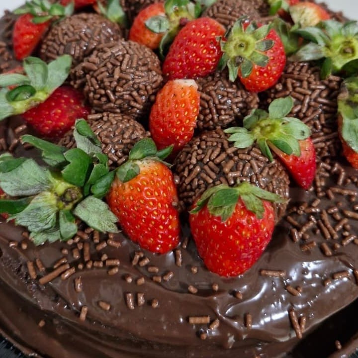 Bolo de chocolate com brigadeiro cremoso e morangos e brigadeiro de docinho como enfeite