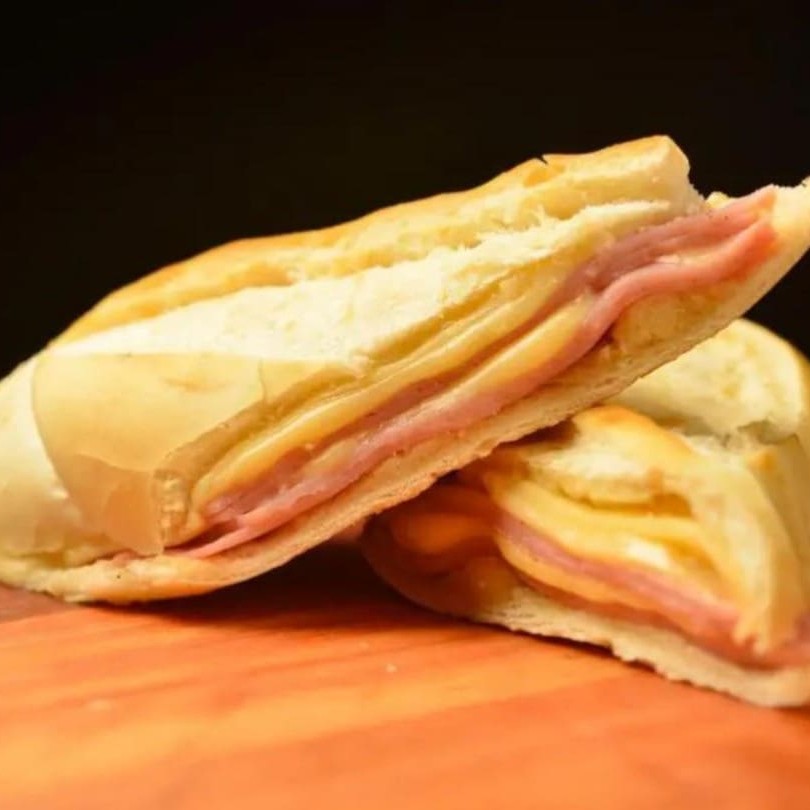O clássico dos clássicos! Pão recheado com presunto e queijo derretido, dourado na chapa até ficar crocante por fora e macio por dentro. Perfeito para um café ou lanche reforçado.