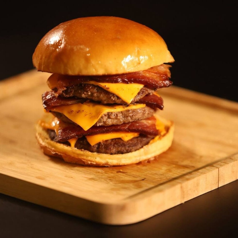 Pao de brioche, 3 bland de 100 gr cada, 3 fatias de queijo cheddar e muito bacon