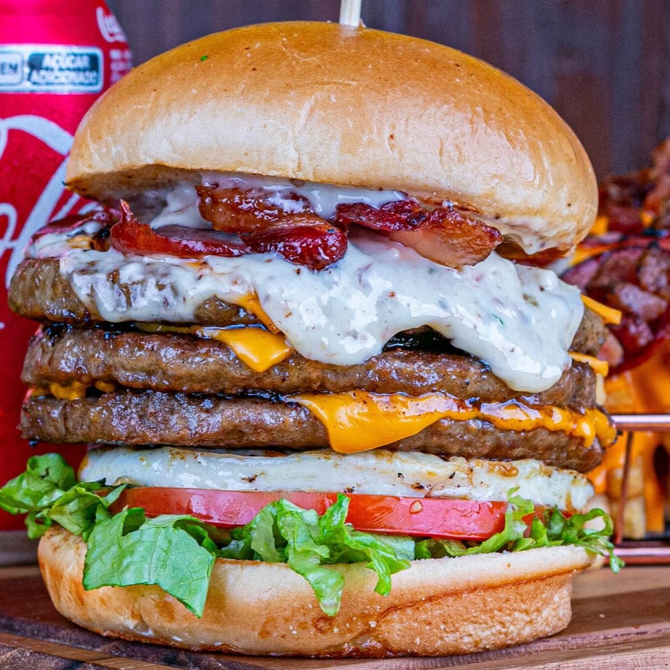 Delicioso e irresistível hambúrguer gourmet de pão brioche.  Recheado com 3 suculentas carnes, queijo derretido em triplo, ovo, bacon crocante, calabresa, fresca salada e uma maionese especial.   Satisfaça sua fome com nossos lanches quentes, saborosos e preparados com o máximo capricho!