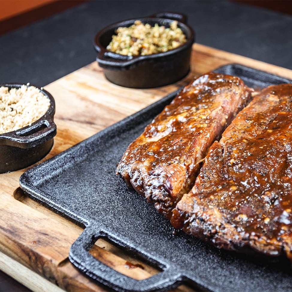 Costela suína (aprox. 550g) preparada com nosso dry rub exclusivo e finalizada com um molho barbecue irresistível. Defumada por 6 horas na lenha frutífera, garantindo sabor e suculência. Acompanha chimichurri e uma farofa de bacon crocante para completar essa experiência gastronômica única!