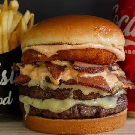 Pão brioche, 2 carnes 100g, 2 mussarela temperada, bacon, cebola empanada e molho gourmet