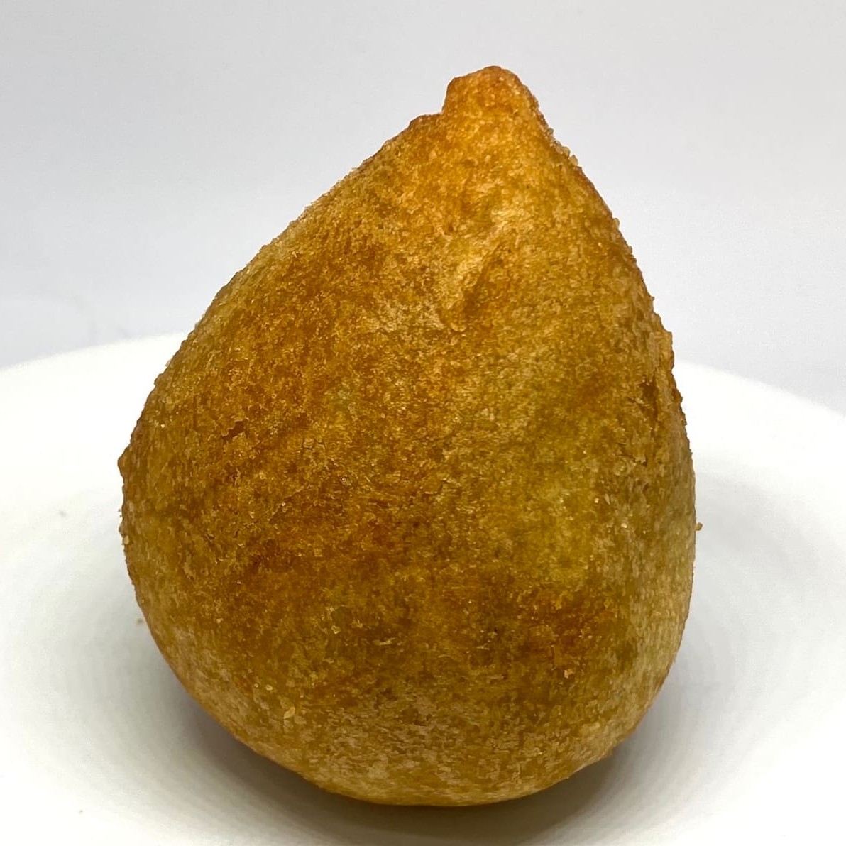 A nossa Coxinha de Frango é a escolha perfeita para quem adora um sabor clássico e delicioso! Feita com frango temperado na medida certa, envolto em uma massa leve e crocante, a coxinha é uma verdadeira iguaria que agrada a todos os paladares.  Com uma textura incrível por fora e um recheio suculento e cheio de sabor por dentro, a Coxinha de Frango é ideal para qualquer ocasião: um lanche rápido,