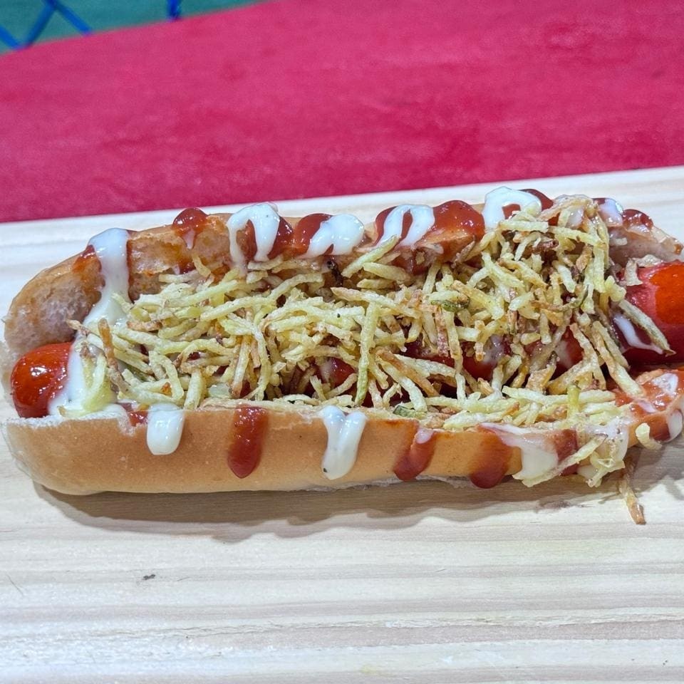 O cachorro quente americano é um lanche delicioso que contém salsicha, caldo, ketchup, maionese e batata palha. É uma combinação de sabores incrível.
